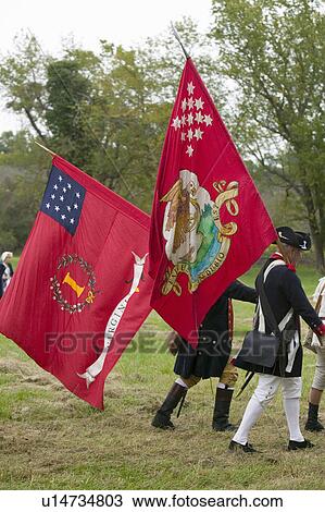 Stock Image - Patriot soldiers march with flags to Surrender Field as part of the 225th Anniversary of the Victory at Yorktown, a reenactment of the siege of Yorktown, where General George Washington commanded 17, 600 American troops and French Comte de Rochambeau lead . Fotosearch