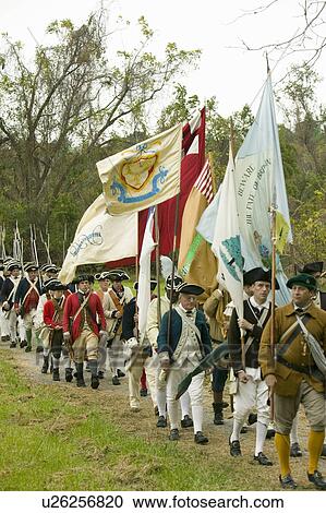 Stock Image - Patriot soldiers with flags march to Surrender Field as part of the 225th Anniversary of the Victory at Yorktown, a reenactment of the siege of Yorktown, where General George Washington commanded 17, 600 American troops and French Comte de Rochambeau lead . Fotosearch