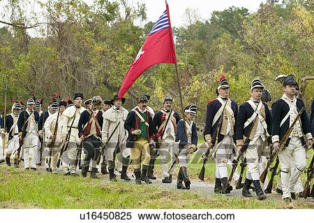 Stock Photography - Patriot soldiers with flags march to Surrender Field as part of the 225th Anniversary of the Victory at Yorktown, a reenactment of the siege of Yorktown, where General George Washington commanded 17, 600 American troops and French Comte de Rochambeau lead . Fotosearch