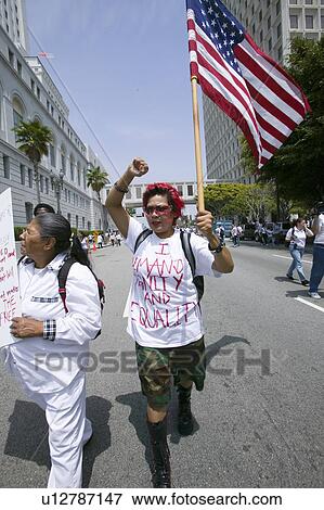 Stock Photo - Protestor carries US flag demanding equality with hundreds of thousands of immigrants participating in march for Immigrants and Mexicans protesting against Illegal Immigration reform by U. S. Congress, Los Angeles, CA, May 1, 2006. Fotosearch