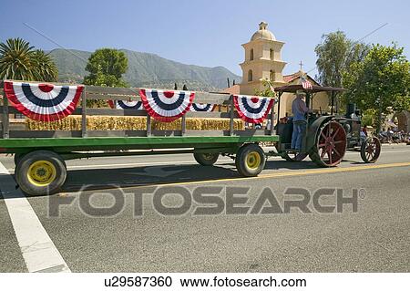 Stock Image - Tractor pulls decorated float down main street during a Fourth of July parade in Ojai, CA. Fotosearch