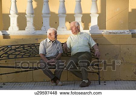 Stock Photo - Two older men talk on bench of village of Southern Spain off highway A49 west of Sevilla. Fotosearch