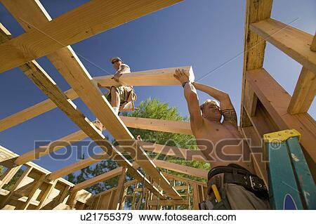 Workers position support beams into framing of house in Southern California View Large Photo Image Stock Photo - Workers position support beams into framing of house in Southern California. Fotosearch