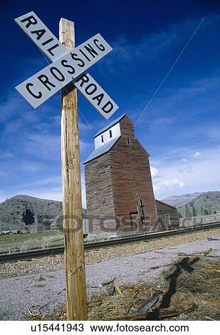 Stock Image - Railroad crossing sign with grain silo in background. Fotosearch