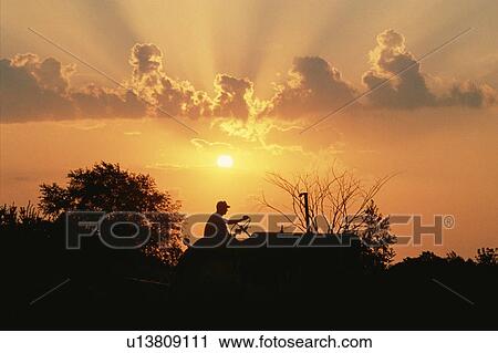 Silhouetted farmer on a tractor at sunset View Large Photo Image Stock Image - Silhouetted farmer on a tractor at sunset. Fotosearch