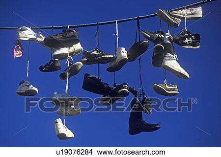 Multiple pairs of shoes flung over electric wire by shoelaces View Large Photo Image Picture - Multiple pairs of shoes flung over electric wire by shoelaces. Fotosearch