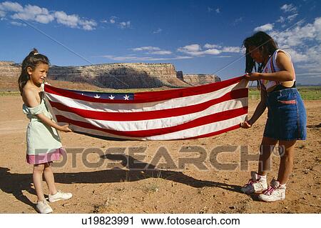 Stock Image - Two girls folding the American flag. Fotosearch