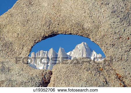 Stock Photograph - The Alabama Hills hole in rock framing snowy mountains at sunrise. Fotosearch