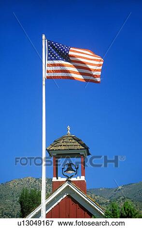 Stock Photo - American flag waving above one room schoolhouse. Fotosearch