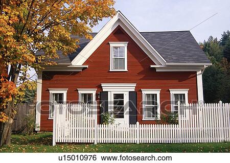 Stock Photograph - Red wooden house with white picket fence in autumn. Fotosearch
