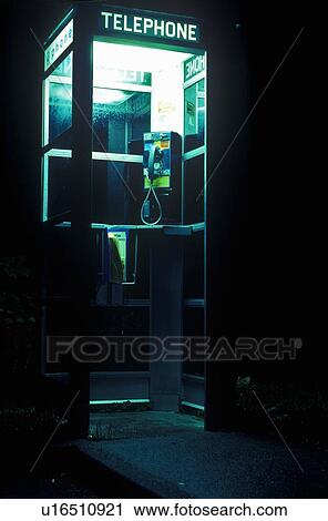Stock Image - Telephone booth at night with interior lights. Fotosearch