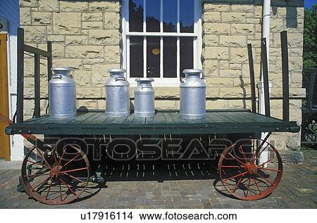 Picture - An old standard gauge steam engine car holds antique milk cans. Fotosearch