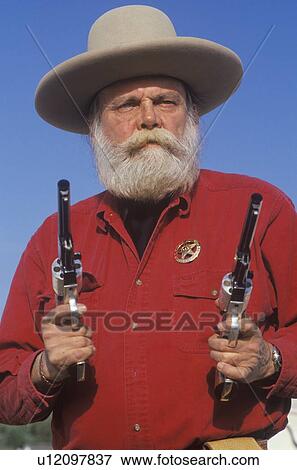 Stock Photo - Old West gunslinger drawing guns during historical reenactment. Fotosearch