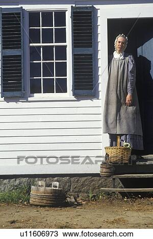 Stock Image - Woman in period clothing in doorway to house in Historic town . Fotosearch