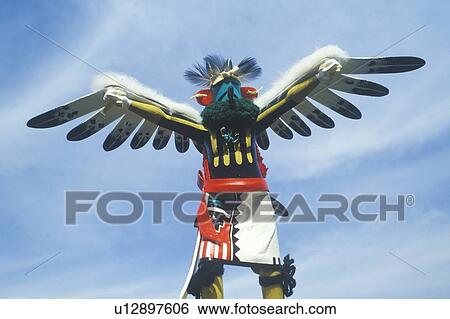 Stock Photograph - Hopi Kachina doll with outstretched winged arms against blue sky. Fotosearch