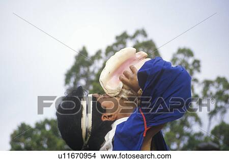 Picture - Native American blowing into conch shell during Xochi Mochi sunrise ceremony. Fotosearch