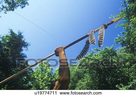 Stock Image - Native American Cherokee holding a spear, Tsalagi Village. Fotosearch