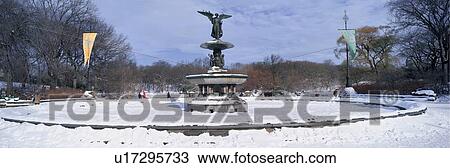 Stock Image - Panoramic view of water fountain covered with fresh winter snow in Central Park, Manhattan, New York City. Fotosearch