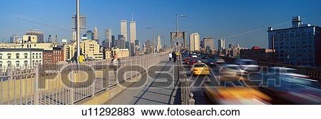 Stock Image - Panoramic view of speeding taxis driving over Brooklyn Bridge to Manhattan. Fotosearch