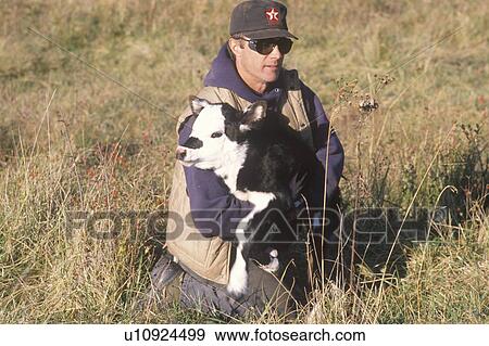 Stock Photo - Cattle farmer holding calf. Fotosearch