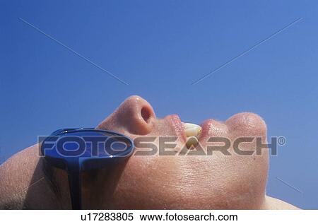 Close-up profile of a sunbather wearing glasses View Large Photo Image Stock Photography - Close-up profile of a sunbather wearing glasses. Fotosearch