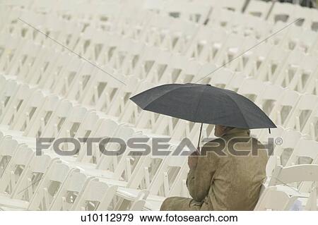 A solo figure holding an umbrella awaiting the opening ceremonies of the Clinton Presidential Library View Large Photo Image Stock Photo - A solo figure holding an umbrella awaiting the opening ceremonies of the Clinton Presidential Library. Fotosearch