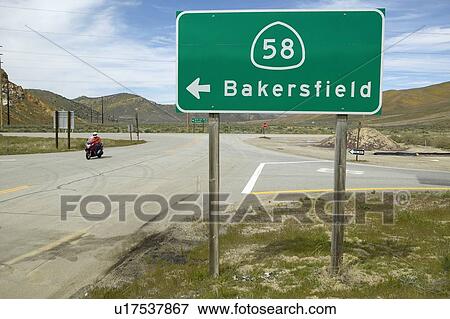 Stock Photo - A motorcycle driving past a road sign. Fotosearch