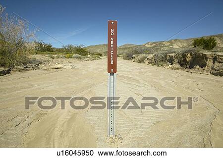 Stock Image - A “No Vehicle” sign warning off-road drivers not to travel up the dry creek bed in Anza Borrego, CA. Fotosearch