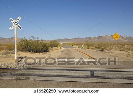 Stock Image - Railroad crossing sign and intersection in Mojave Desert of Southern California. Fotosearch