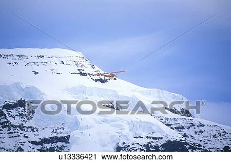 Stock Image - “Super Cub” Piper bush airplane flies in St. Elias National Park and Preserve, Wrangell Mountains. Fotosearch