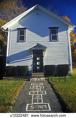 Stock Image - Small schoolhouse with hopscotch pattern on sidewalk. Fotosearch