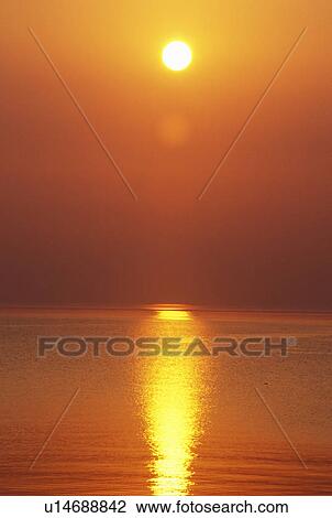 Stock Image - Sun Setting Over The Ocean. Fotosearch