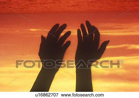 Stock Photo - Sunset sky behind silhouette of two hands . Fotosearch