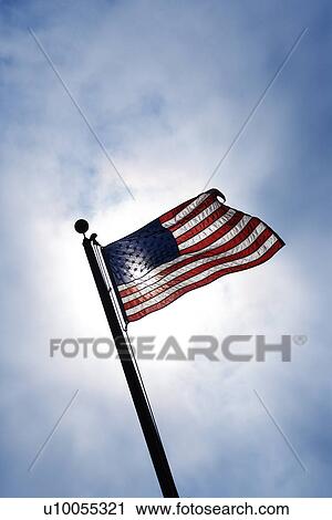 American flag blowing in breeze against blue sky. View Large Photo Image Stock Image - American flag blowing in breeze against blue sky.. Fotosearch