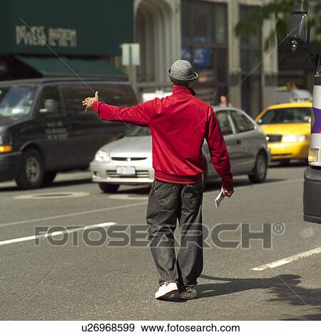 Stock Photo - Man in red jacket hailing a cab, New York City. Fotosearch
