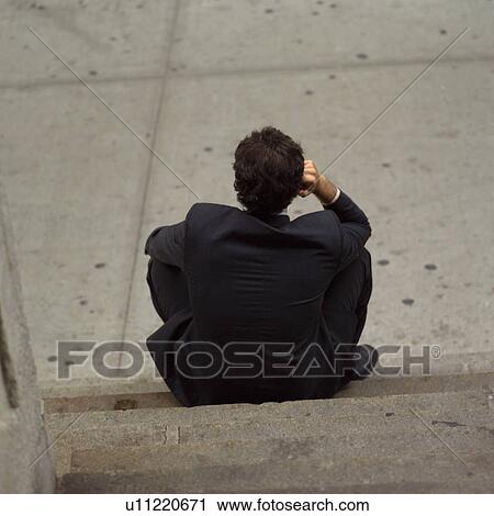 Stock Image - Rear view of business man sitting on steps, New York City. Fotosearch