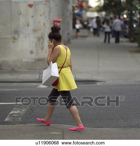 Stock Photo - Woman in yellow outfit walking in East Village, New York City. Fotosearch