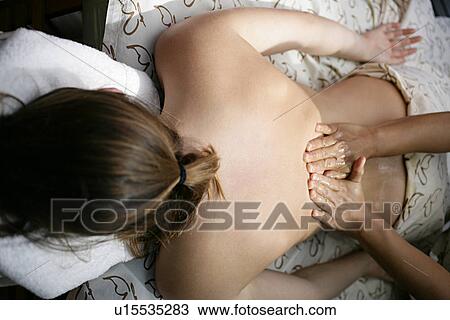 Stock Image - A massager massaging a woman’s back.. Fotosearch