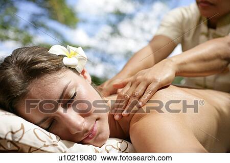 Stock Image - A massager massaging a young woman’s back.. Fotosearch