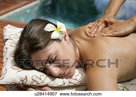 Stock Photo - A massager massaging a young woman’s back.. Fotosearch