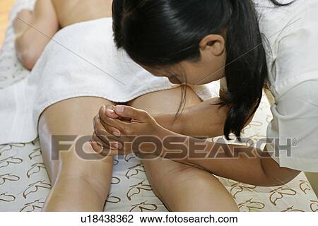 Stock Image - A masseuse massaging a woman’s back.. Fotosearch