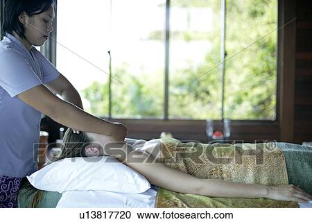 Stock Image - A masseuse massaging a woman’s face.. Fotosearch
