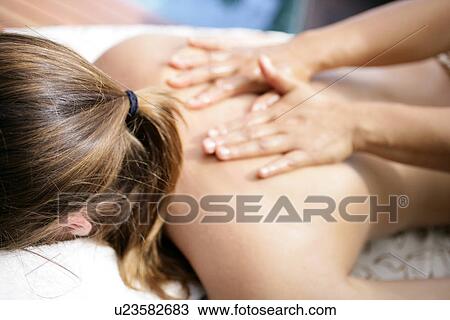 Stock Image - A person massaging a woman’s back.. Fotosearch