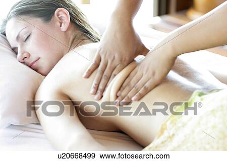 Stock Photo - A person massaging a young woman’s back.. Fotosearch