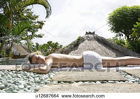 A young woman lying on stony ground for sun bathing. View Large Photo Image Picture - A young woman lying on stony ground for sun bathing.. Fotosearch