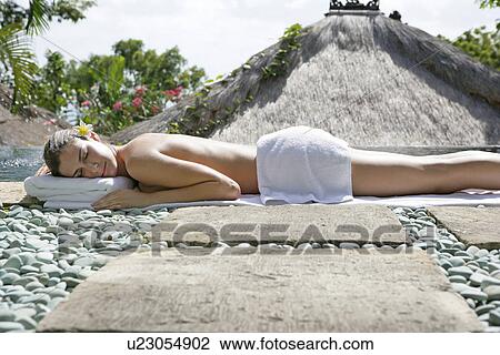 A young woman lying on stony ground sun bathing. View Large Photo Image Stock Image - A young woman lying on stony ground sun bathing.. Fotosearch