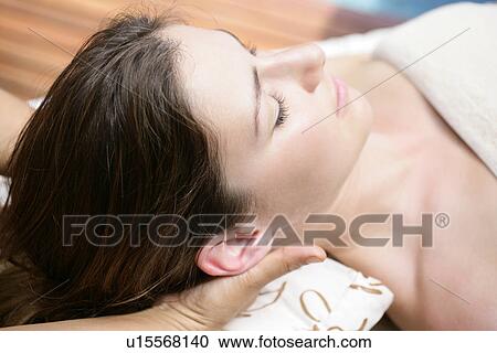 Stock Image - A young woman lying with eyes closed.. Fotosearch