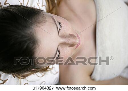 Stock Photo - A young woman lying with eyes closed.. Fotosearch