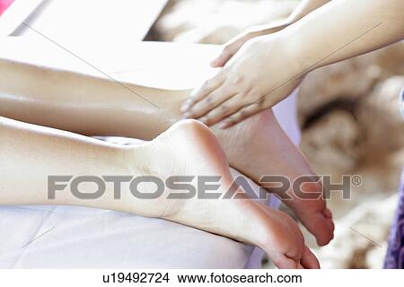 Picture - Close-up of a person massaging a woman’s leg.. Fotosearch