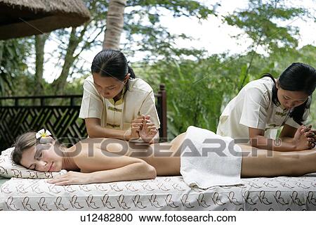 Two masseuses massaging a woman. View Large Photo Image Stock Image - Two masseuses massaging a woman.. Fotosearch